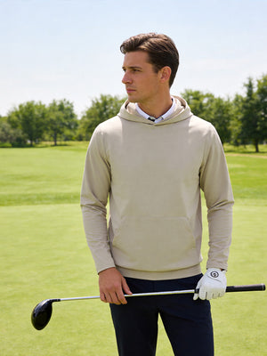 Outdoor shot of a model holding a golf club, wearing the khaki light dry fit stretchy sweatshirts hoodies with a relaxed fit.