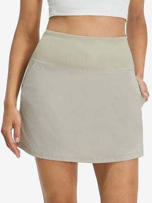 Front lower body shot of model wearing oyster gray women's stretch a-line golf skort with 7 pockets