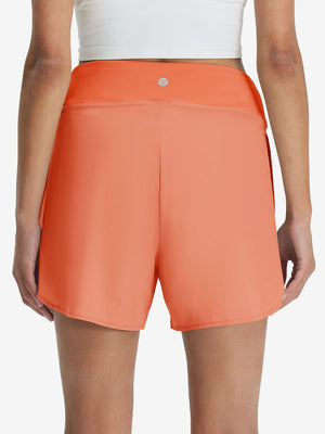 Back lower body shot of model wearing peach pink women's gym golf shorts with liner pocket