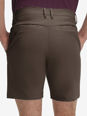 Back lower body shot of model wearing tobacco brown flat front hybrid golf shorts