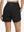 Back lower body shot of model wearing black women's high waist 2 in 1 quick dry shorts with 7 pockets