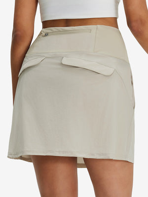 Back lower body shot of model wearing oyster gray women's stretch a-line golf skort with 7 pockets