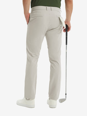 Rear lower-body: model in light khaki stretch quick dry casual golf pants with 4 pockets holding golf club in right hand.