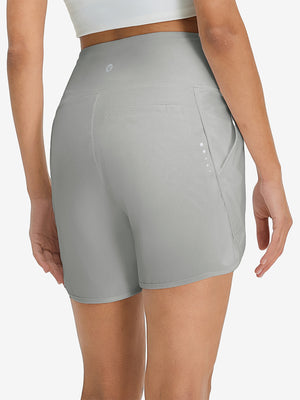 Back lower body shot of model wearing glacier grey women's high waist 2 in 1 quick dry shorts with 7 pockets
