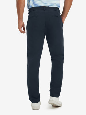 Back view of model wearing water-resistant golf stretch nylon pants, tailored stretch fit in navy.