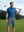 Model holding a golf club on course, styled in 4-way stretch performance solid shorts with dark grey
