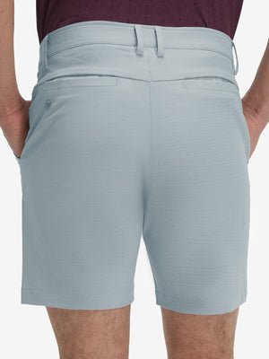 Back lower body shot of model wearing newport blue flat front hybrid golf shorts