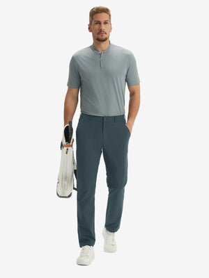 Full-body front: model in grey blue stretch quick dry casual golf pants with 4 pockets carrying golf bag by hand.