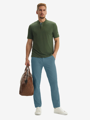 Full-body front: model in blue stretch quick dry casual golf pants with 4 pockets carrying golf bag by hand.