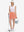 Front full body shot of model with golf gear wearing peach pink women's stretch a-line golf skort with 7 pockets