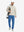 Model carrying a tennis bag, wearing colony blue lightweight flat front casual trousers in full-body view.