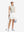 Front full body shot of model with golf gear wearing white women's moisture-wicking athletic tennis skirts