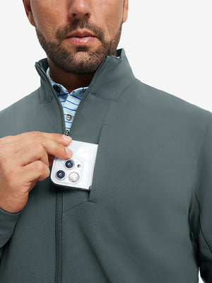 Close detail of hand in chest pocket of water-resistant zip up golf jacket in dark dusty blue.