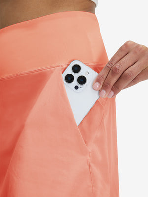 Detail view of side pocket on peach pink women's stretch a-line golf skort with 7 pockets