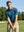 Model in four leaf clover performance jersey print polo preparing to tee off, half-body shot