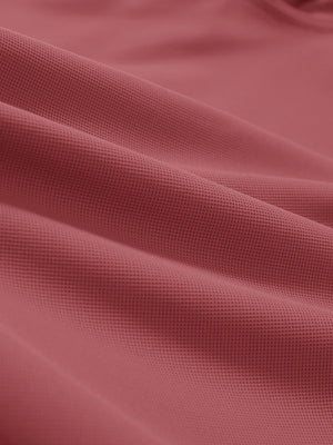 Close-up texture of brick red dry fit waffle textured collared golf shirts fabric showing weave detail.