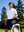 Outdoor shot of a model with a golf bag, wearing the white moisture-wicking short sleeve henley shirt with a relaxed fit