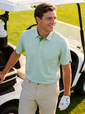 Model in relaxed pose on outdoor course wearing emerald feather weight jacquard polo shirts